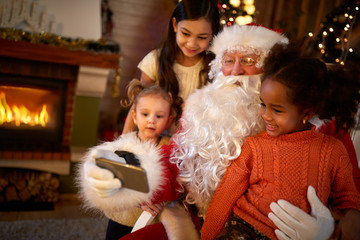 Fototapeta na wymiar Santa Claus making selfie with three cute girls