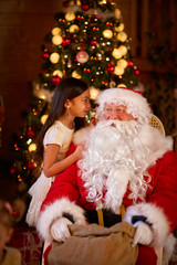 Fototapeta na wymiar winter holiday concept - girl telling wish Santa Claus.