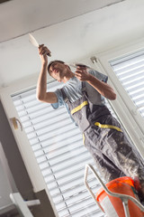 Construction worker wearing worker overall with wall plastering tools renovating apartment house....