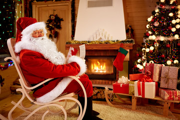 Obraz premium Santa Claus enjoying and reading children wishes for x-mas.
