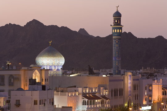 Elevated dusk view of buildings along the Corniche, latticed buildings and Mutrah Mosque, Muscat, Oman