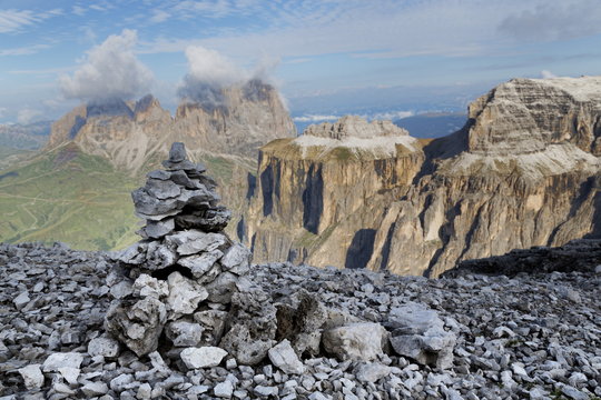 Stone cairn on Sass Pordoi mountain in the Dolomites near Canazei, with cloud covered Sassolungo mountains in the distance, Trentino-Alto Adige 