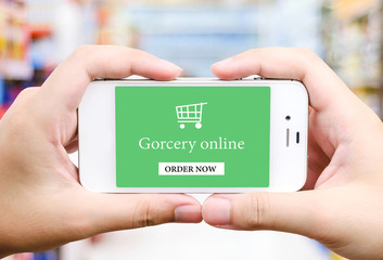 On line shopping on smart phone screen over blur supermarket
