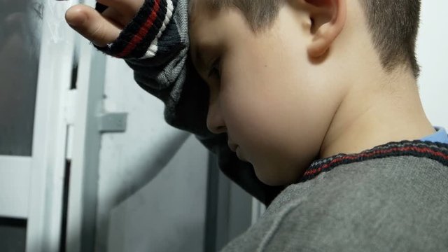sad boy punished by his parents, leaned at the window