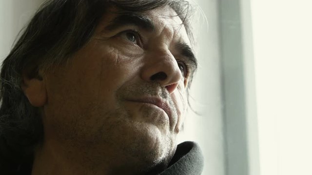 portrait of a white adult man leaned near the window, looking out