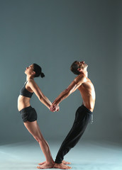 Young couple practicing acro yoga on mat in studio together