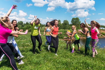 Group of excited women crossing the finshline  a marathon running on grassy land in park.