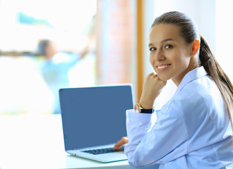 Beautiful young smiling female doctor sitting at the desk