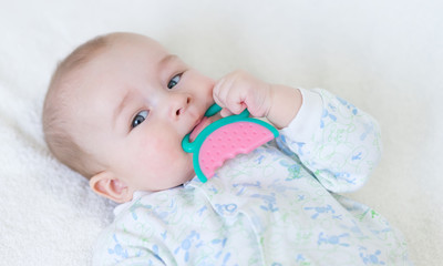 painful teething in infants, baby close-up with a toy.