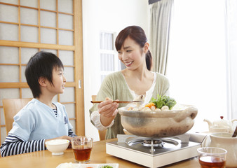 Mother and son sitting around Japanese hot pot