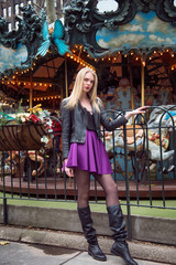Fashion beauty model woman posing on carousel in amusemet park.  