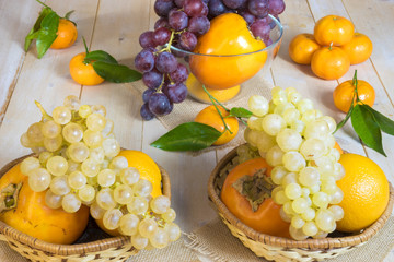 grapes, kaki and tangerine in wicker baskets