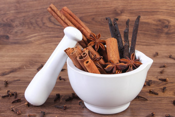 Fragrant anise, cinnamon and vanilla sticks in mortar on rustic board