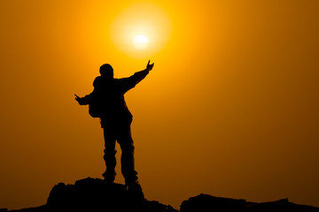 Man with arms extended toward heaven at sunrise ,success or prayer concept warm tone