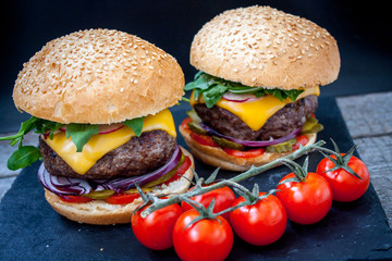 Homemade beef burgers on a black slate background.