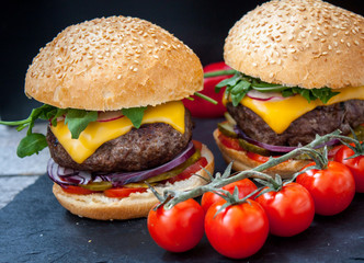 Homemade beef burgers on a black slate background.