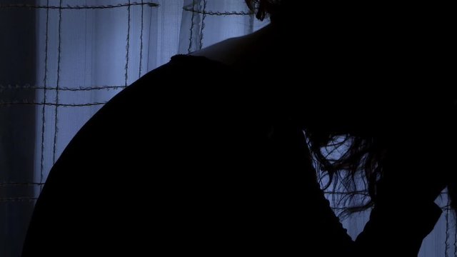 desperate woman stays with her thought and regrets in a dark room