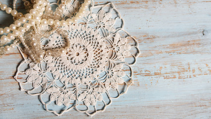 Shabby chic background for wedding with vintage pearl necklaces and lace on old, painted wood background. Top view with copy space.