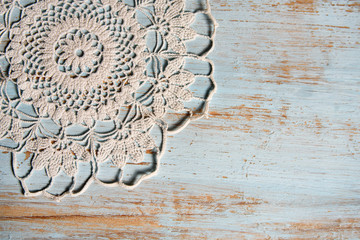 handmade lace on shabby chic, painted, blue wood. Macrame close-up, top view with copy space. Wedding or holiday background.
