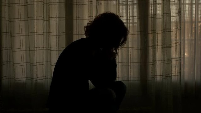 woman sat on her bed seems to be exhausted and overcome by her bad feelings