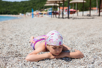 European young girl laying on the sandy beach with closed eyes. Sunbathing on seashore