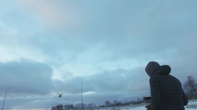 Drone operator flying multicopter outdoors at cold winter. Slow motion.