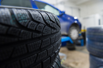 Detail of a winter tyre with a car in the background