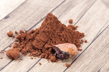 Cocoa beans and powder on wooden plank.
