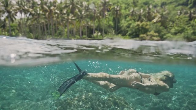Beautiful underwater 50/50 footage of a girl snorkeling in a shalow bay in Nusa Penida, Indonesia.