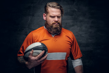 Bearded rugby player holds game ball.