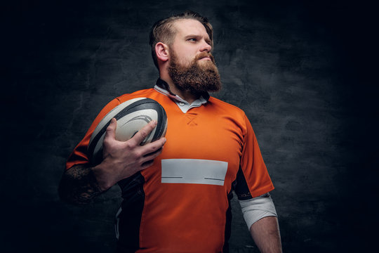 Bearded rugby player holds game ball.