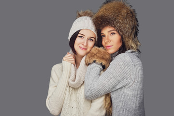 Two women in winter clothes on white background.