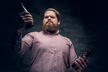 Portrait of a fat bearded male holds beer bottles.