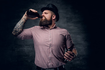 Bearded male in a cylinder hat, drinking beer from a bottle.