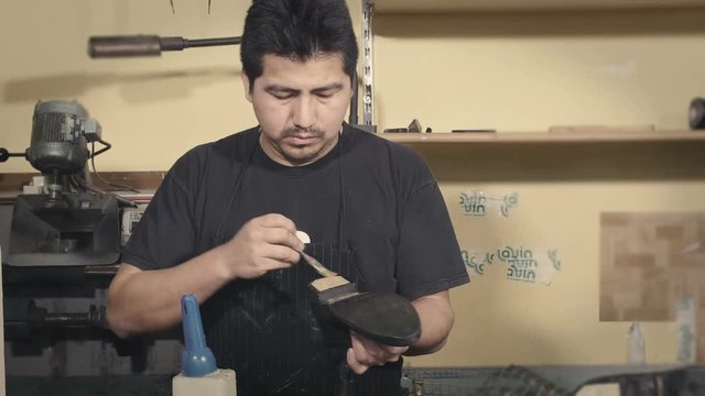 skilled shoemaker brushing a sole for a boot