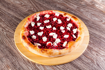 open pie with cranberries on a wooden board and background, the