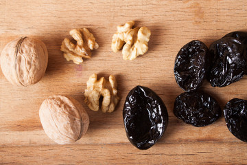 Dry prune and walnut on wood desk. 