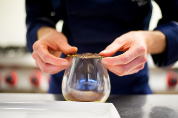 Chef preparing a dessert in a glass made of cream and chocolate