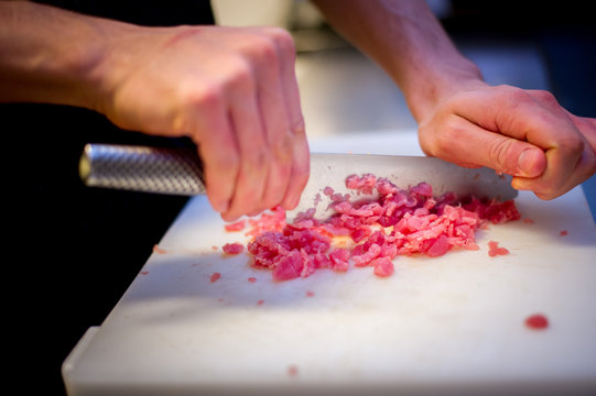 Chef mincing raw meat to prepare a steak tartare
