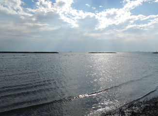 sun over the sea in clouds. Reflections on the water and the waves rolling