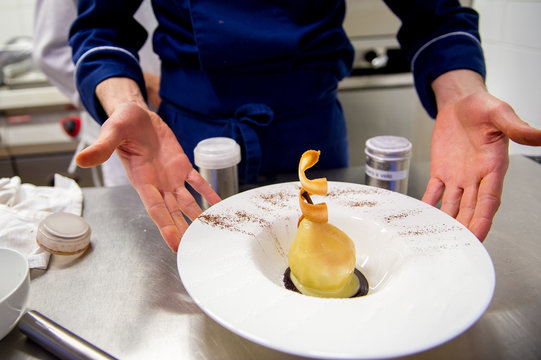 Chef's hands presenting a dessert made of boiled pear