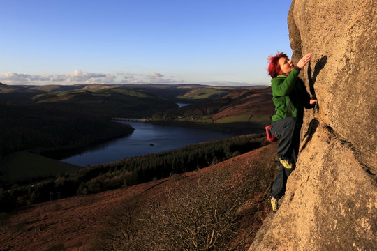 a climber on the gritstone cliffs above the Derwent Reservoir, Peak District, Derbyshire