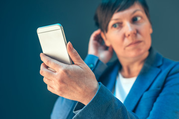 Businesswoman with short hair checking hairstyle using mobile ph