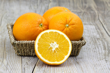 fresh oranges in a basket on old wooden background