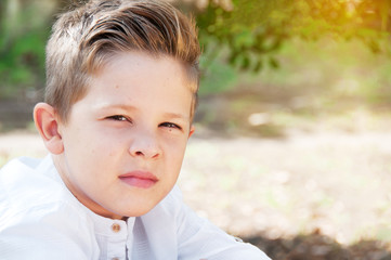 Portrait of a beautiful boy closeup. Cute schoolboy in the park,