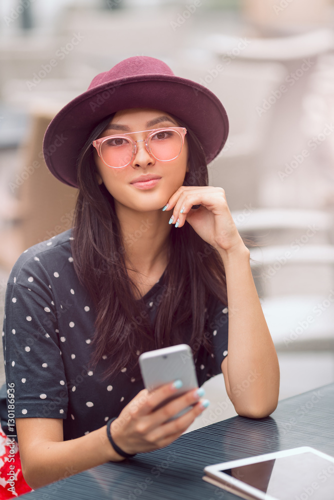 Wall mural smiling young woman looking at smart phone in cafe shop