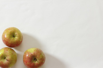 Red apples on a white table cloth background.