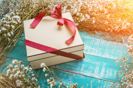 Wrapped gift boxes with presents and flowers on aged wooden back