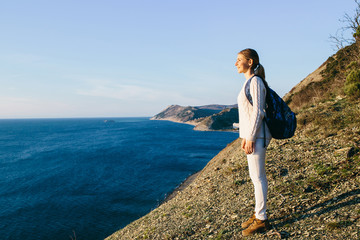 young woman traveler on top of a cliff on seaside. Travel, Holidays, Freedom and Lifestyle Concept