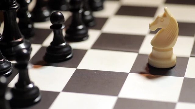 Color footage of a chess match, with white knight facing black pieces.